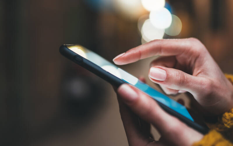 Person's hand typing on a mobile phone screen