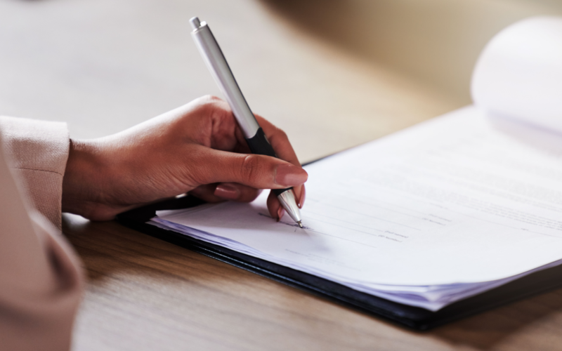 Woman filling out a paper document using a pen