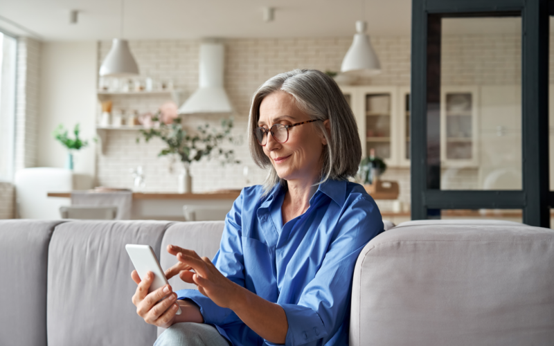 Older woman using a mobile phone whilst sitting on her sofa